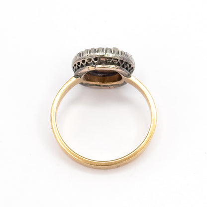 Back view on white, the ring standing upright so the open gallery beneath the bezel and the darker silver halo mount are seen from behind, with the slim gold shank forming a full circle.