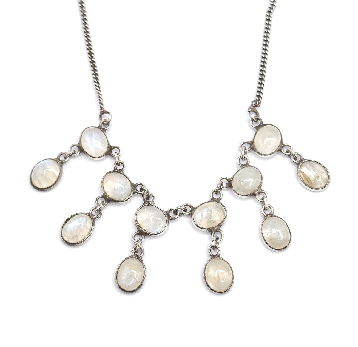 Straight-on symmetrical view of the whole fringe centred on white, the curb chain rising to both upper corners while the oval moonstone bezels mirror each other in linked, stepped tiers.