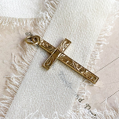 Gold cross pendant on a textured white fabric background