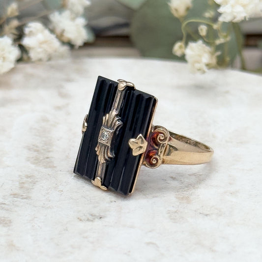 Gold and black ring on a marble surface with blurred floral background