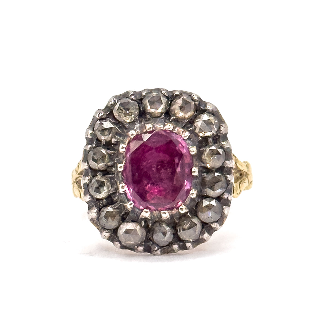 Off the hand against a plain white ground, the face is seen straight on, the pink sapphire held in prongs within its silver-set diamond halo, with the gold shoulders just visible at each side.