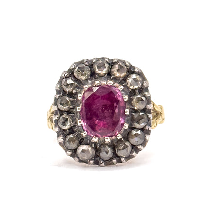 Off the hand against a plain white ground, the face is seen straight on, the pink sapphire held in prongs within its silver-set diamond halo, with the gold shoulders just visible at each side.
