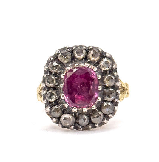 Off the hand against a plain white ground, the face is seen straight on, the pink sapphire held in prongs within its silver-set diamond halo, with the gold shoulders just visible at each side.