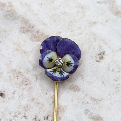 Floral stickpin with purple and yellow flower on a marble surface