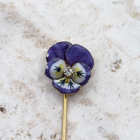 Floral stickpin with purple and yellow flower on a marble surface
