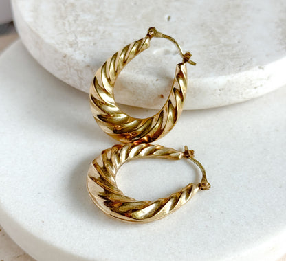 Close side-on view of the two hoops propped against a white stone riser, the upper one standing on edge so the hinged post and catch wire at its top read clearly against the pale surface.
