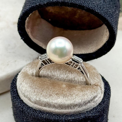 Pearl ring in a black jewelry box on a white surface with a blurred background