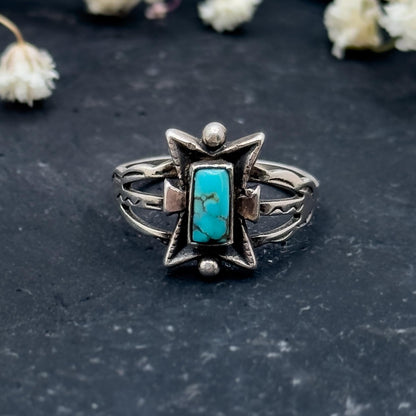Silver ring with turquoise stone on a dark surface with dried flowers