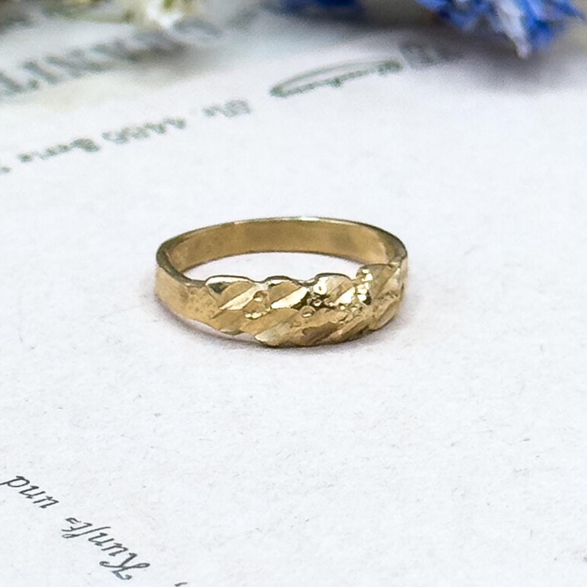 Gold ring on a piece of paper with floral elements in the background
