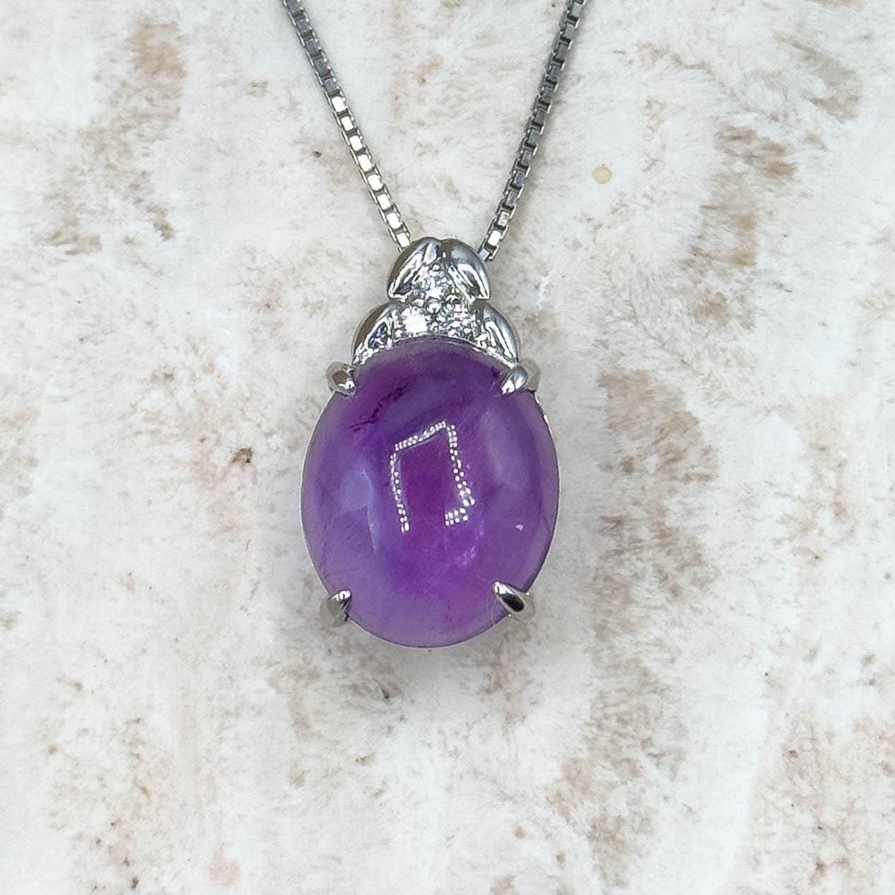 Purple pendant necklace on a textured white surface