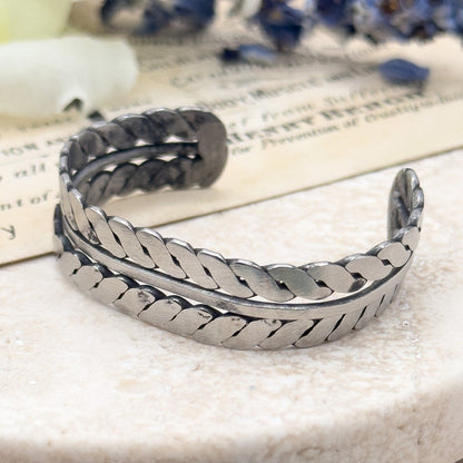 Silver bracelet on a marble surface with flowers in the background Native American Childs bracelet cuff