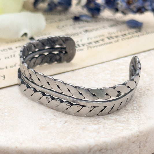 Silver bracelet on a marble surface with flowers in the background Native American Childs bracelet cuff