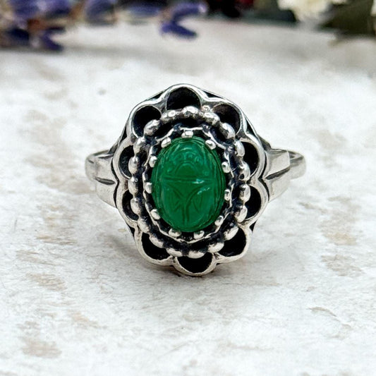 Silver ring with a green gemstone on a textured surface