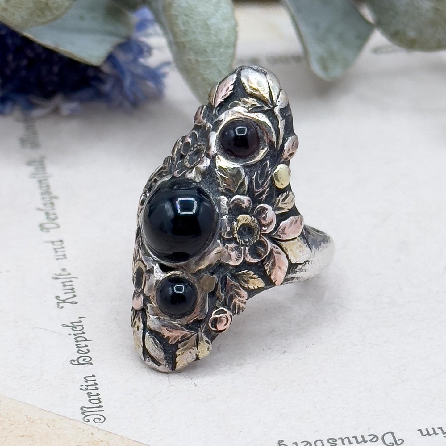 Decorative ring with black stones on a textured surface