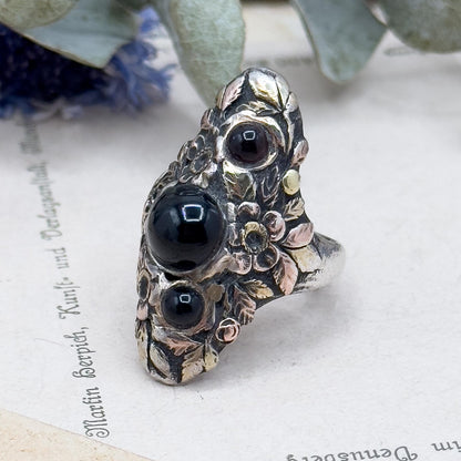 Decorative ring with black stones on a textured surface