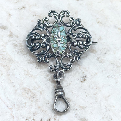 Decorative silver brooch with a central gemstone on a textured white background