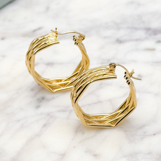 Gold hoop earrings on a marble surface