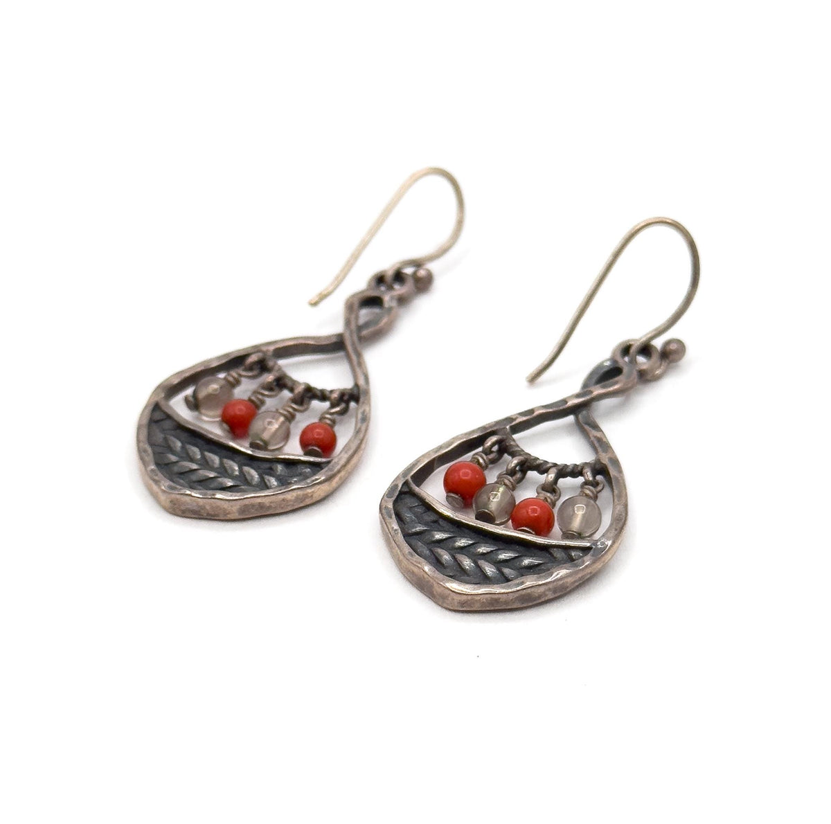 Both earrings on a plain white background, tilted so the hooks curve up to the right and the hammered teardrop backs and dark braided panels face the camera, beads hanging inside each frame.