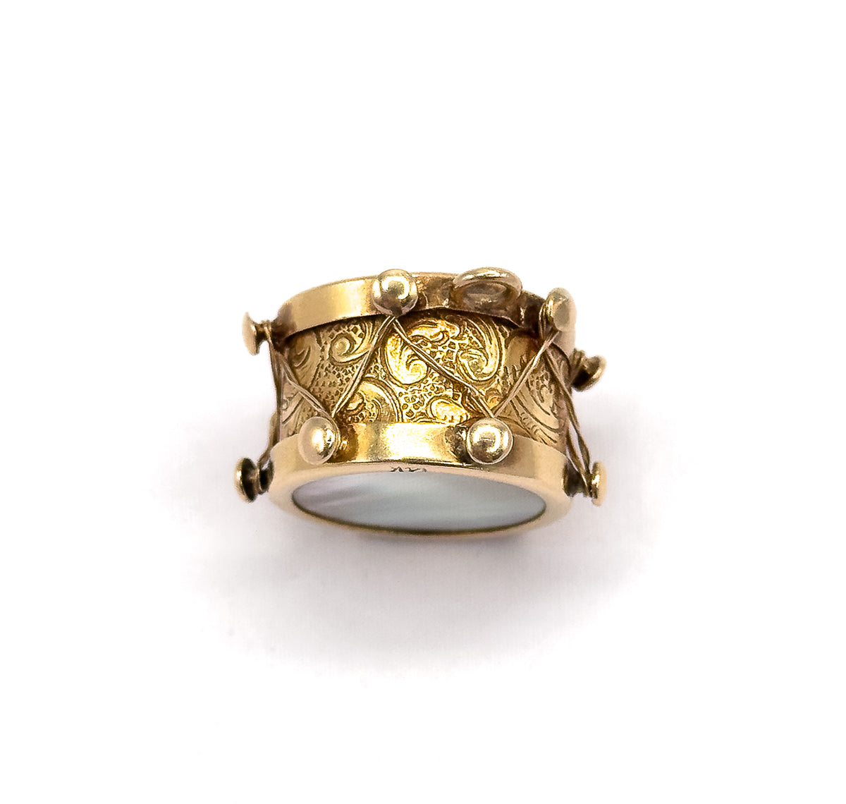 Tipped forward so the drum is viewed from slightly below, revealing the second mother of pearl face on the underside rim while the scrolling engraved side fills the centre.