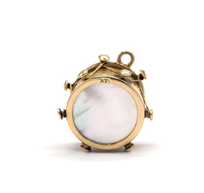 Facing the viewer square-on with the bail standing at the top, the round mother of pearl face fills the frame and the 14K stamp is legible on the gold side band above it.