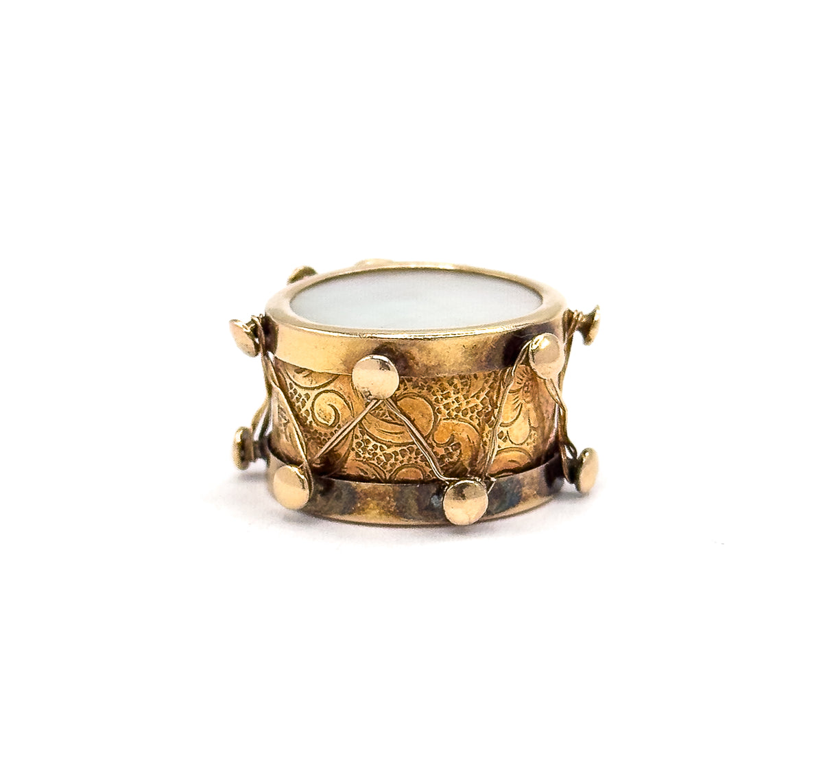 Shown smaller in the frame and almost level, so the full ring of round knobs along both rims and the zigzag thread crossing the scroll-engraved side read clearly beneath the pale iridescent face.