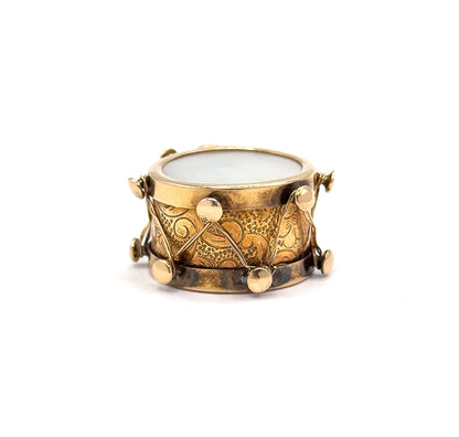 Shown smaller in the frame and almost level, so the full ring of round knobs along both rims and the zigzag thread crossing the scroll-engraved side read clearly beneath the pale iridescent face.