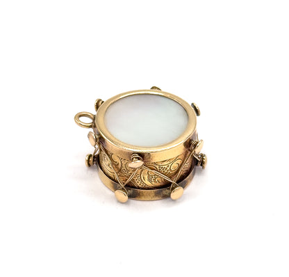Angled from above at close range, the pale mother of pearl face reads almost circular inside its raised gold rim while the bail peeks out at the left edge.
