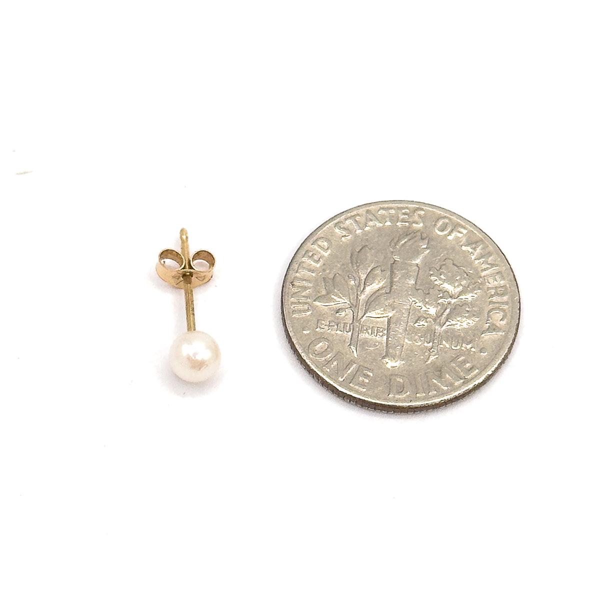 A single stud shown beside a dime for scale, the round white pearl no wider than the coin's lettering, with its yellow gold post and butterfly back above.