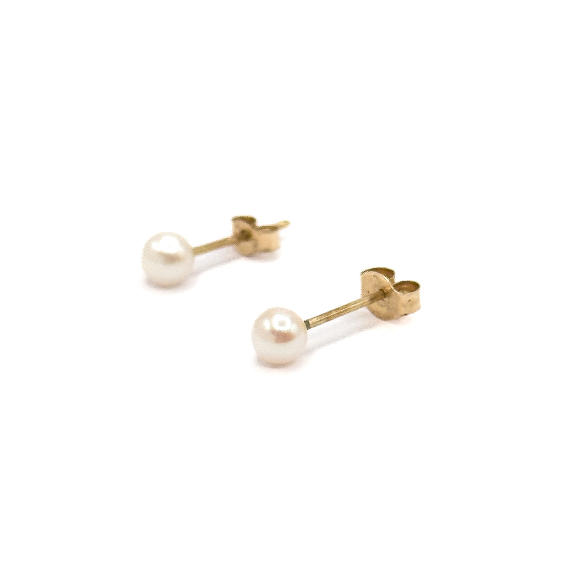 The pair set wide apart on a plain white ground, one stud higher than the other, with the flat face of each yellow gold butterfly back turned toward the camera behind its round white pearl.