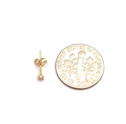 A single stud lies on its side beside a dime, showing the full post, butterfly back and the round pink glass stone in its prongs at a scale the coin makes clear.