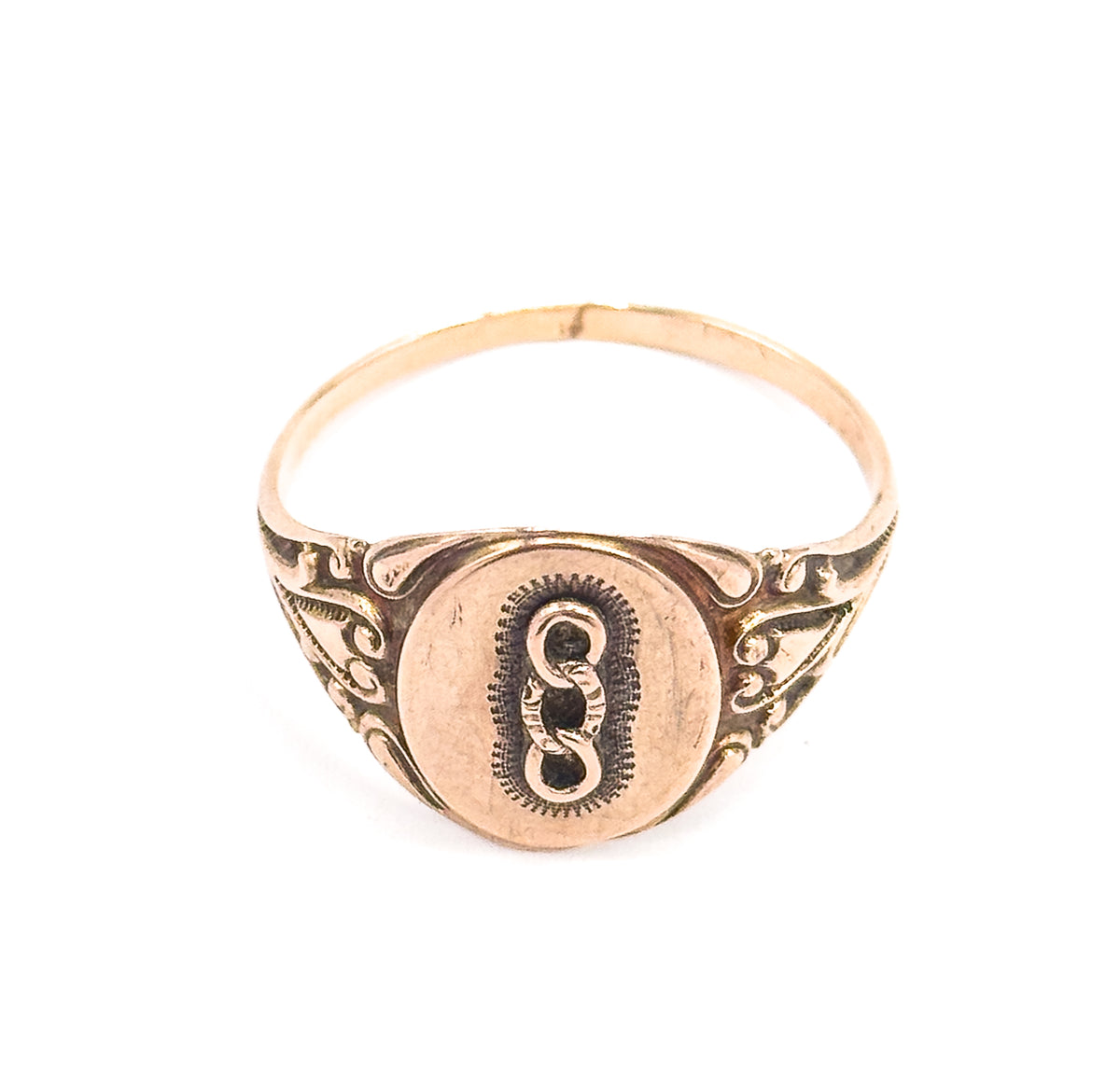 The ring stands upright off the hand against a plain white background, showing the full round of the shank behind the oval face and its scrolled shoulders.