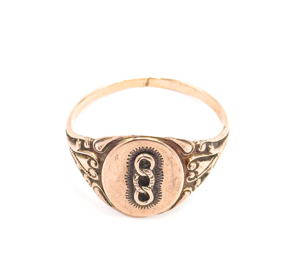 The ring stands upright off the hand against a plain white background, showing the full round of the shank behind the oval face and its scrolled shoulders.