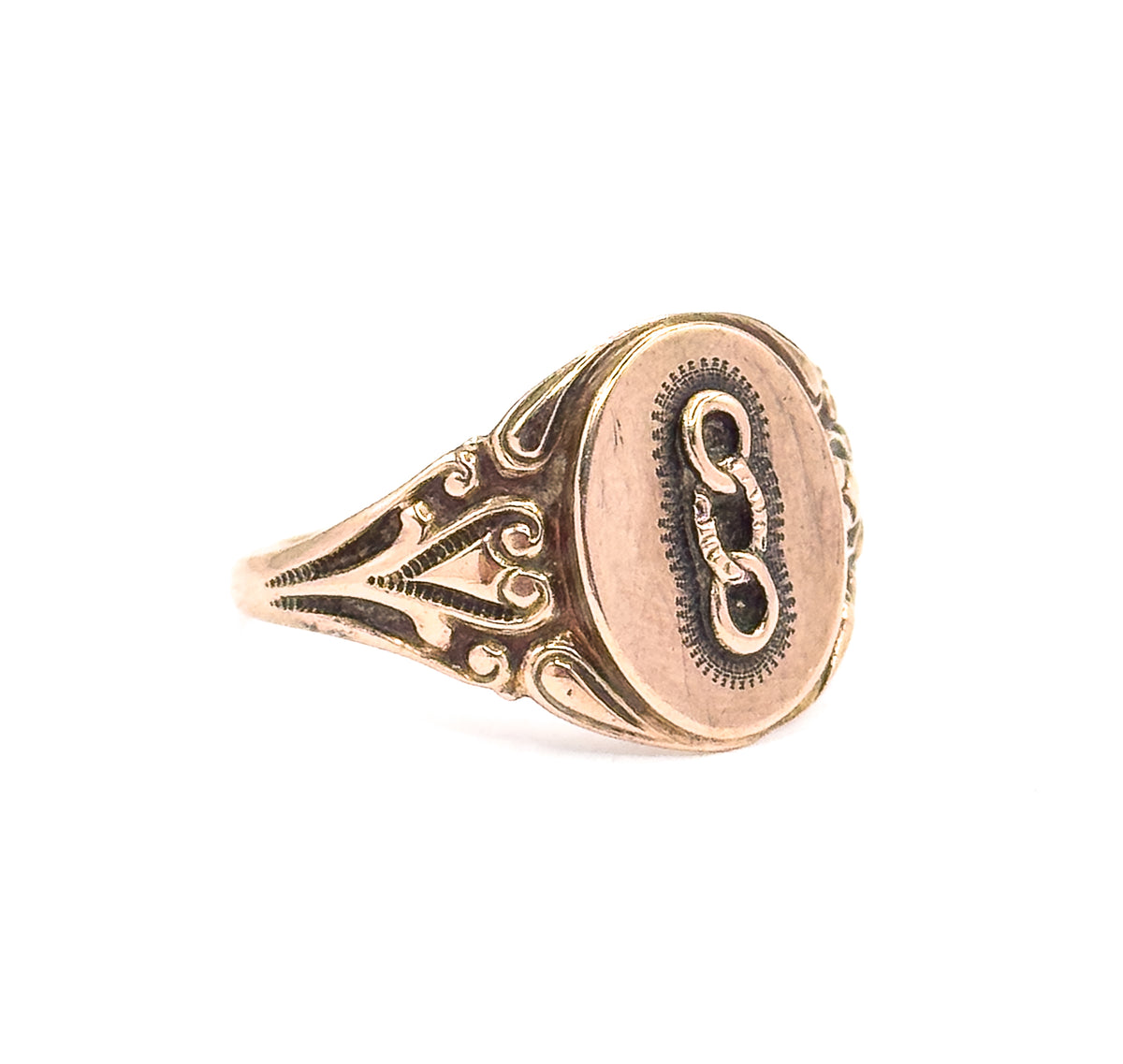 Angled three-quarter view from the side, where the scrollwork on the shoulder stands out in relief and the face tilts away, showing how the oval sits raised above the tapering shank.