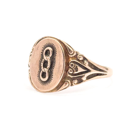 Near-frontal three-quarter view in which the three-link emblem and its finely textured oval surround are fully legible on the face, with one scrolled openwork shoulder alongside.