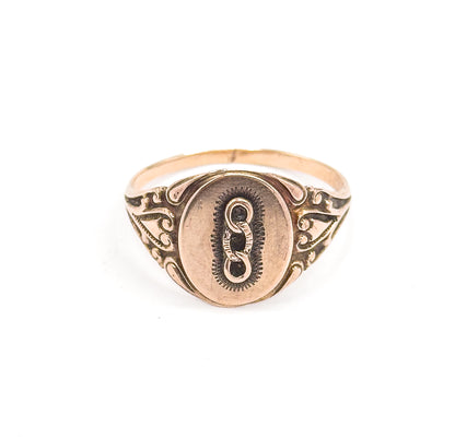 Fully face-on and upright, the oval face sits centred with the three-link emblem and stippled border, flanked by matching scrolled shoulders rising from the slim yellow gold shank.