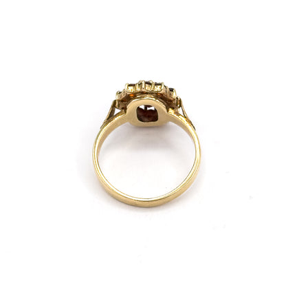 Rear view looking through the open shank, the underside gallery showing the oval garnet's back exposed in its yellow gold setting with prongs visible around the halo.