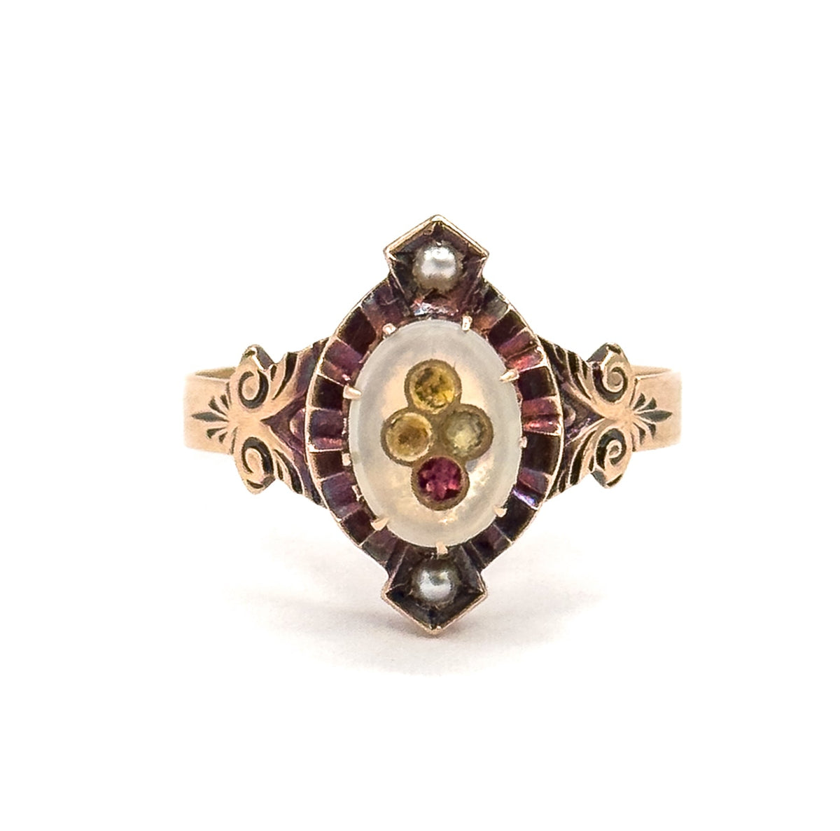 Straight-on view of the face against white, the oval milky glass paste centre holding a small cluster of yellow and pink stones within a pink inlay border, a seed pearl at each point.