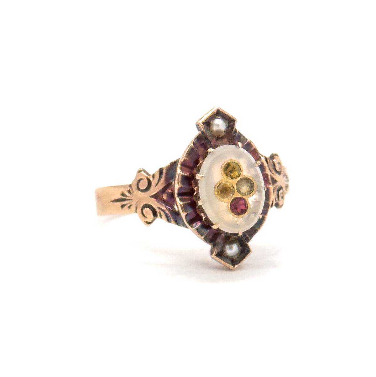 Standing upright against a plain white background, the ring is seen off the hand at a slight angle, showing the oval face, seed pearls at top and bottom points, and engraved shoulders meeting the shank.