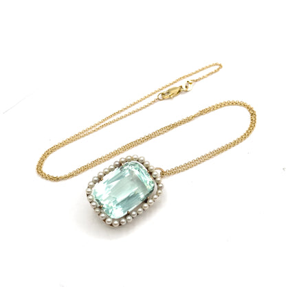 The whole necklace laid out in an oval loop on white, with the cushion-cut aquamarine pendant and its seed pearl halo at the bottom and the clasp at the top.