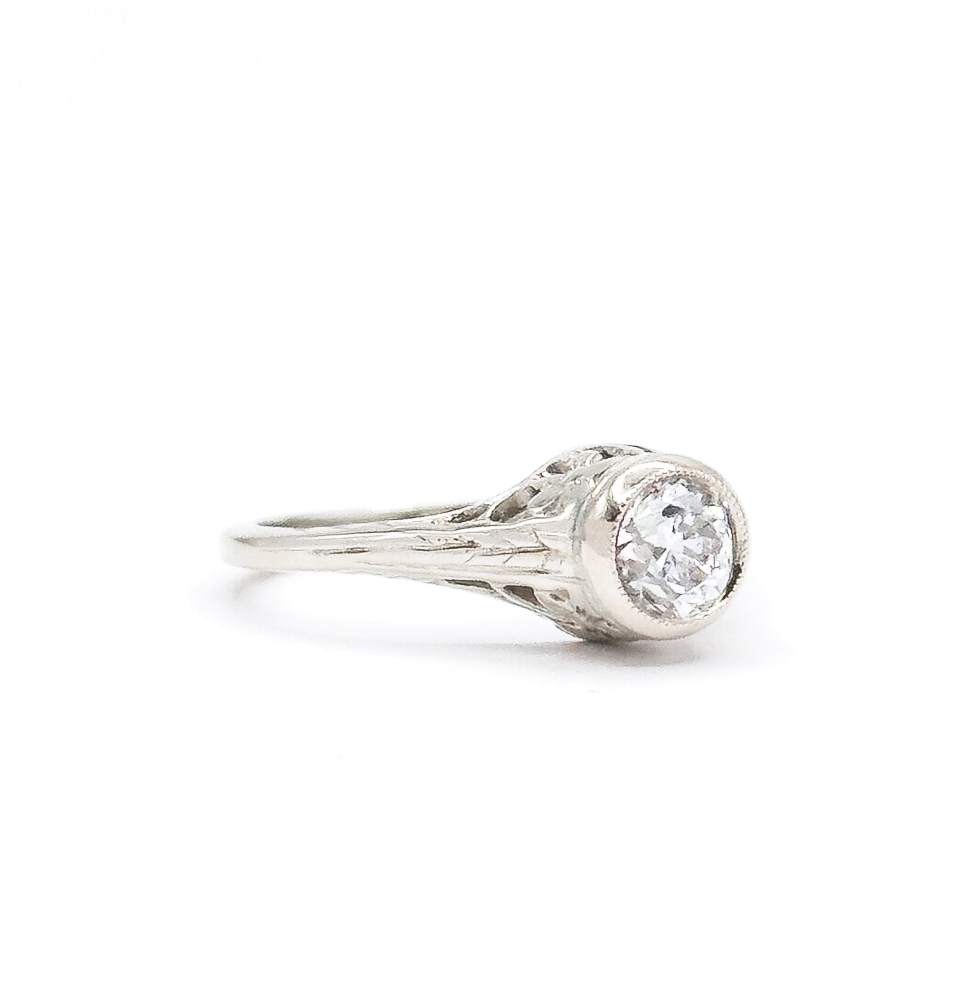Almost the same view with slightly different angle, turned to show the pierced gallery openings beneath the bezel and the engraved flower shoulder alongside the raised diamond.