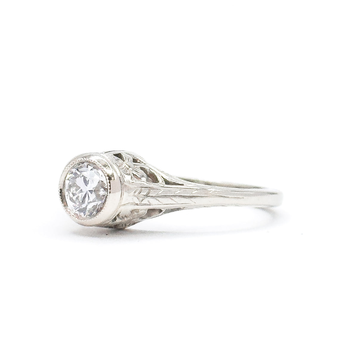 Side profile against white, showing how high the bezel lifts the old European cut diamond above the band, with the engraved shoulder tapering down into the slim white gold shank.
