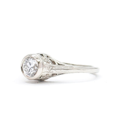 Side profile against white, showing how high the bezel lifts the old European cut diamond above the band, with the engraved shoulder tapering down into the slim white gold shank.