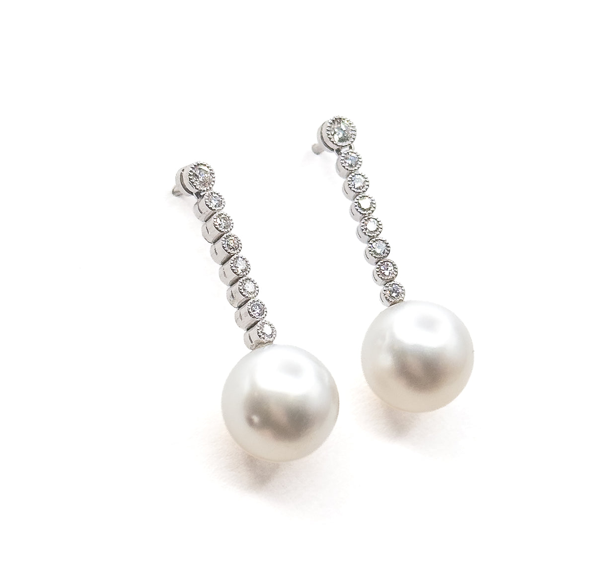 Both earrings side by side on white with the diamond lines curving slightly like crescents, a bright highlight sitting on the upper left of each pearl drop and grey shading beneath.