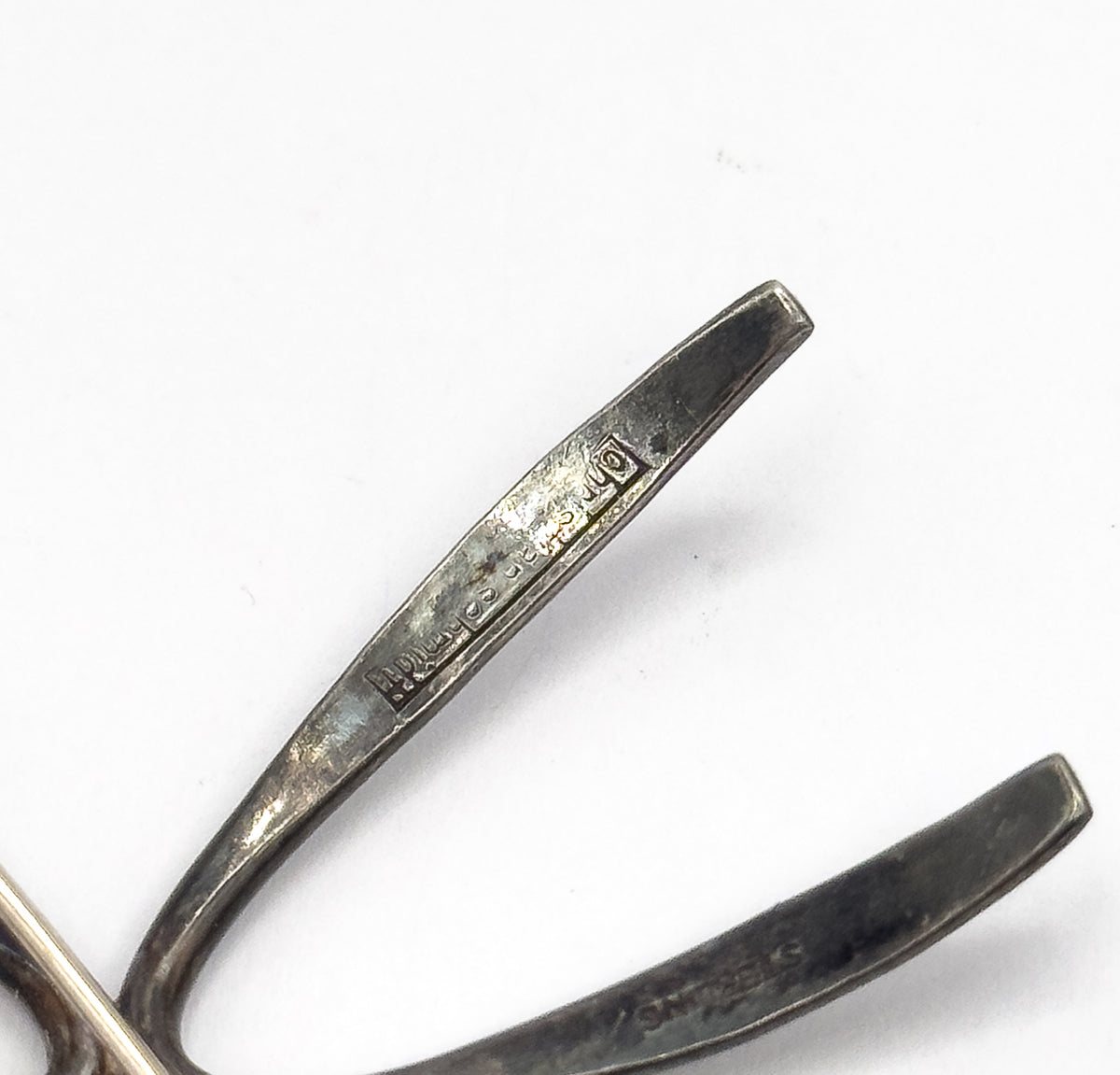 Close view of the back of one tapering ray, where a maker's stamp reading Christian Schmidt is struck into the silver, with a second ray below marked Sterling.