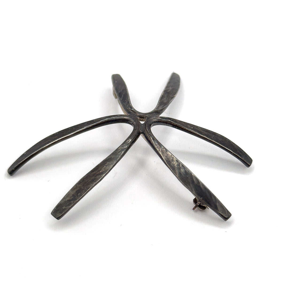 Angled back view from the tip end, the rays lifting and curving away from the flat plane so the starburst's sculptural depth shows, with the coiled hinge and catch at opposite ray tips.