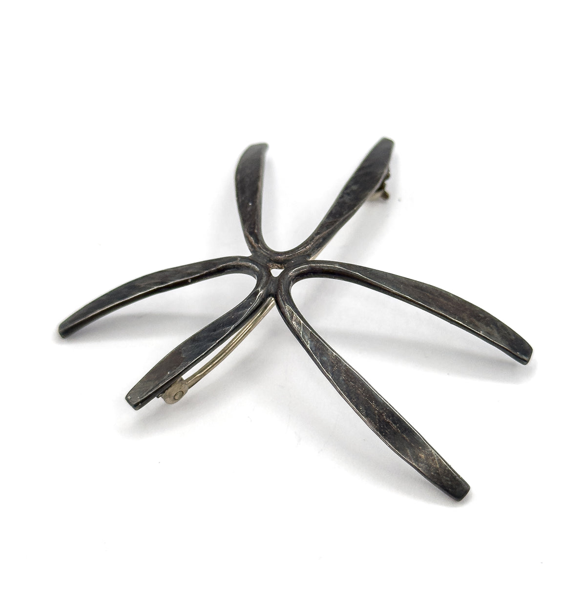 Back of the brooch laid flat and angled so all five tapering rays splay across the frame, the hinge at the upper ray tip and the hook catch at the lower left one.
