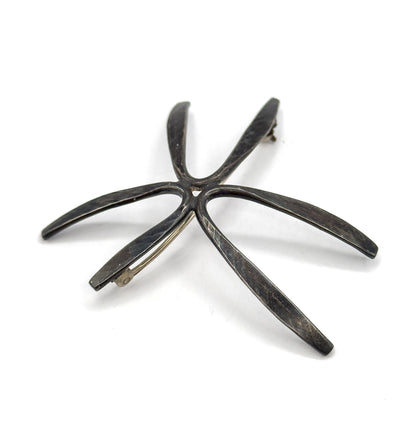 Back of the brooch laid flat and angled so all five tapering rays splay across the frame, the hinge at the upper ray tip and the hook catch at the lower left one.