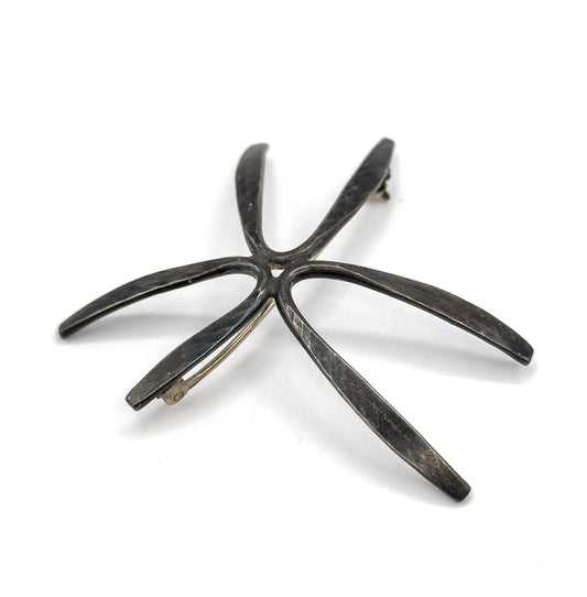 Back of the brooch laid flat and angled so all five tapering rays splay across the frame, the hinge at the upper ray tip and the hook catch at the lower left one.