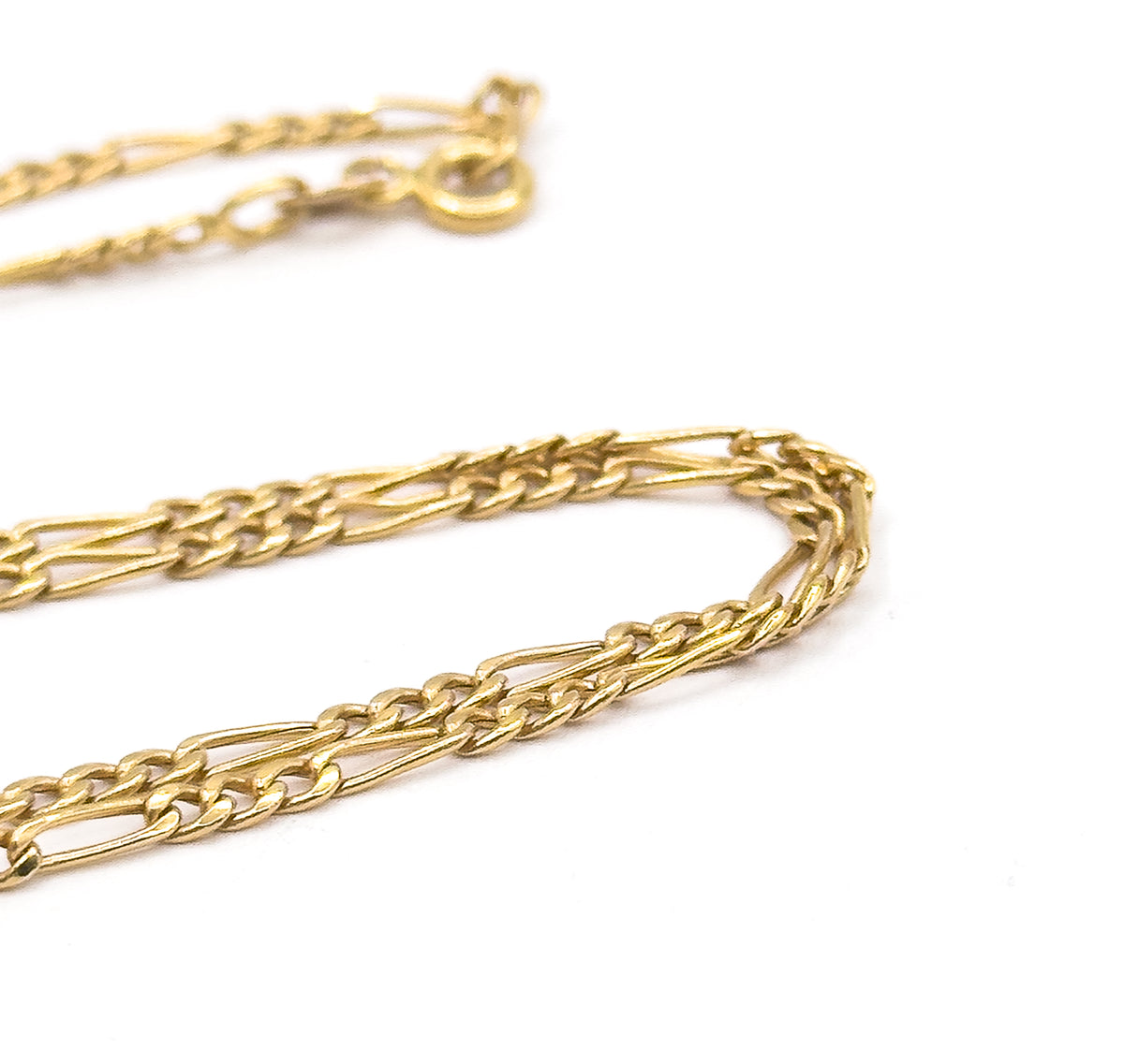The chain curves back on itself in a long hairpin loop on white, with the spring ring clasp and jump ring soft-focused in the far background.