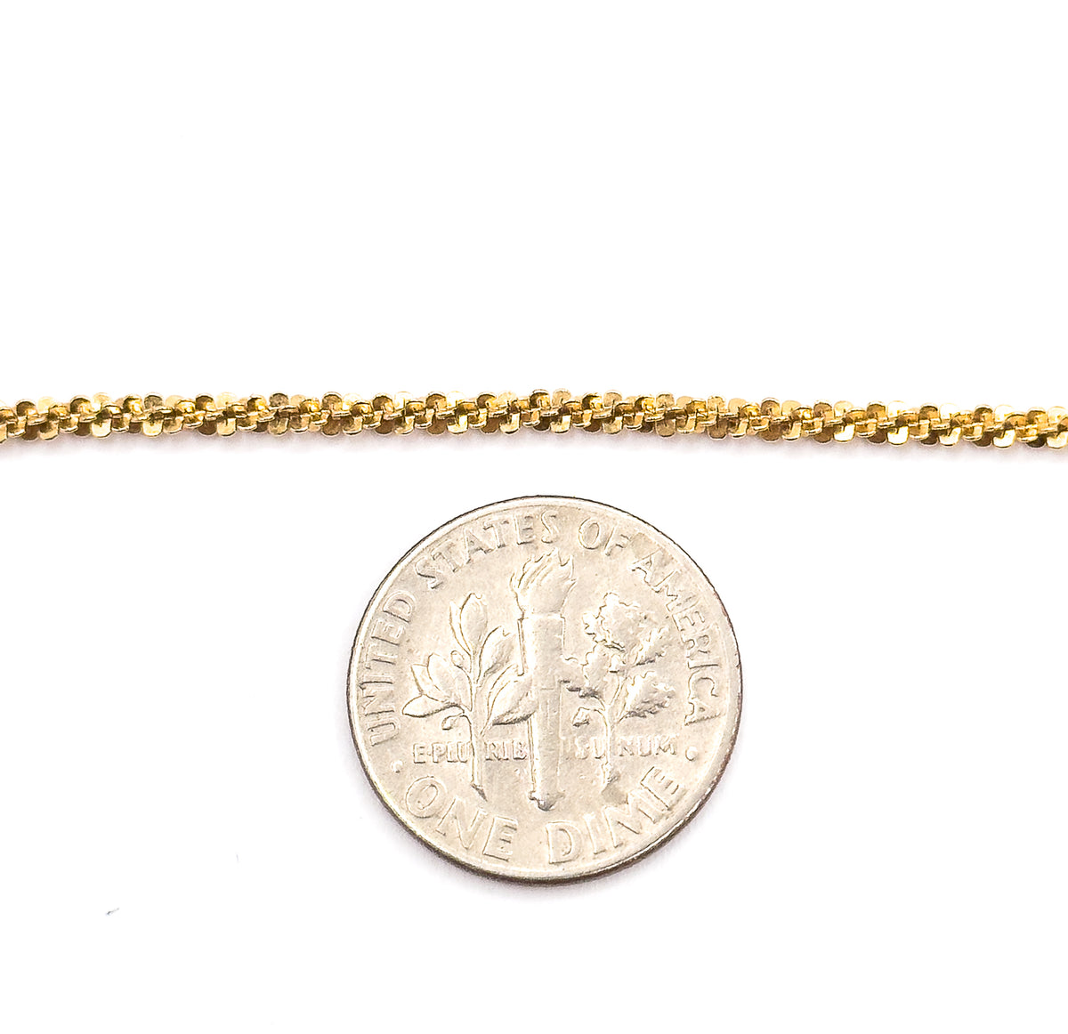 A straight length of the textured yellow gold chain laid above a US dime for scale, the coin showing the links are only a little wider than its milled edge.